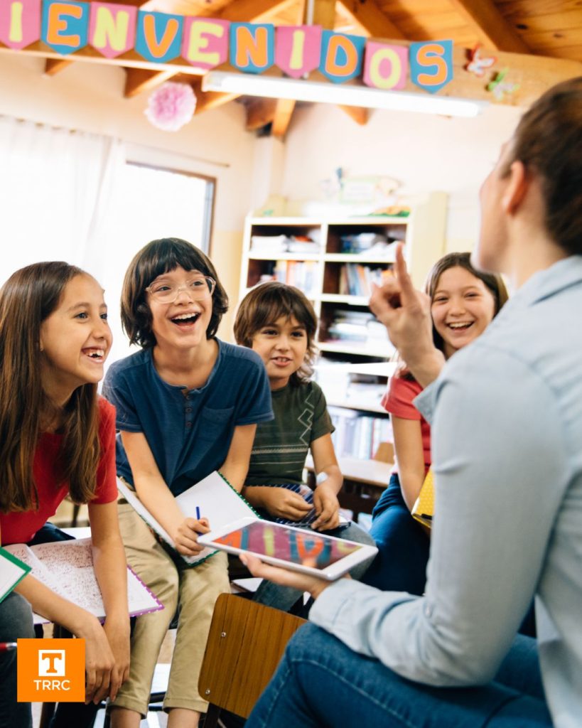 4 students in a classroom listening to a teacher speak
