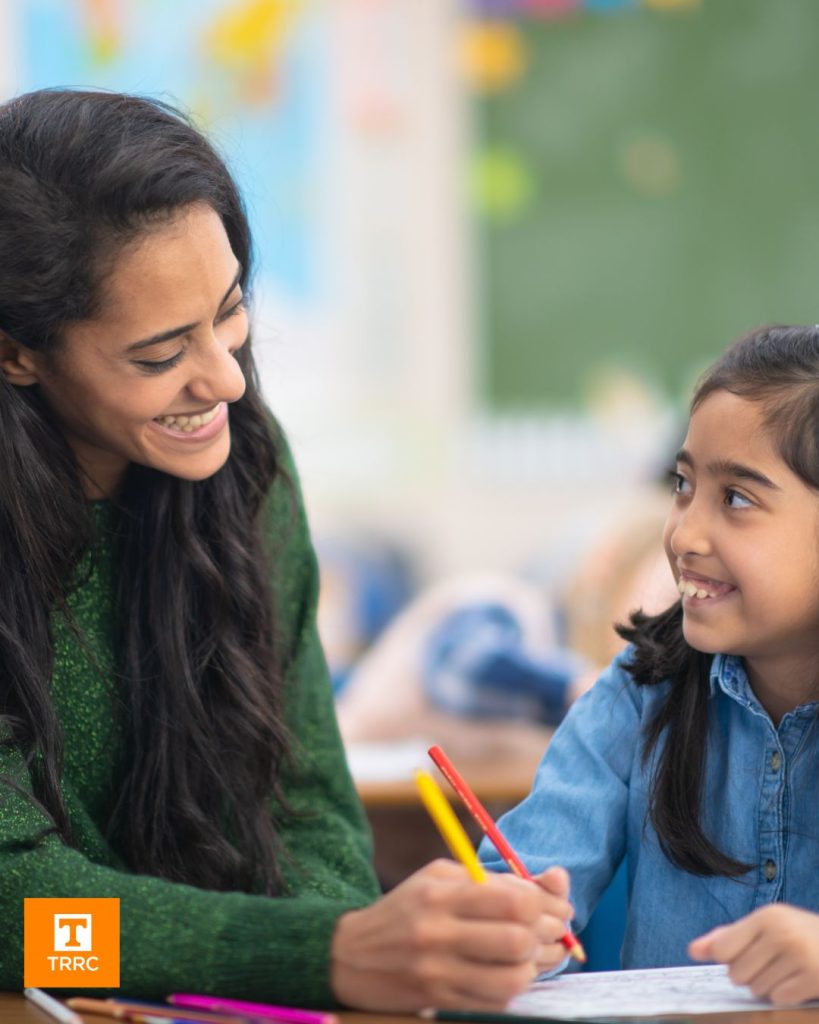 A teacher writing alongside a student in a classroom