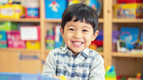 A young boy in a classroom smiling