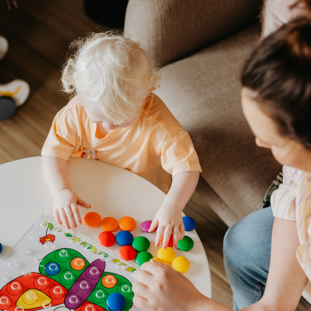 A parent and a child playing with circular, multi-color toys